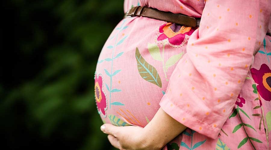 Sliderbild Doula Agnieszka Schwangerenbauch im Blumenkleid
